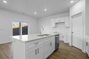 Kitchen featuring white cabinets, recessed lighting, a center island with sink, dark wood-type flooring, and stainless steel dishwasher