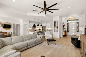 Living room with a chandelier, light wood finished floors, recessed lighting, and ceiling fan