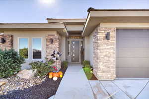 Doorway to property featuring stone siding, stucco siding, and an attached garage
