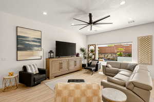 Living room featuring a textured ceiling, ceiling fan, light wood-type flooring, and recessed lighting
