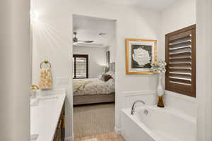 Ensuite bathroom featuring light wood finished floors, vanity, and a bath