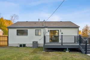 Back of property with brick siding, a deck, and roof with shingles