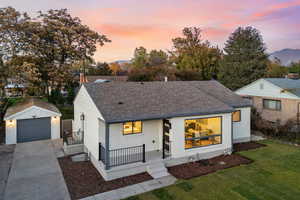 View of front of house with roof with shingles, brick siding, concrete driveway, and an outbuilding