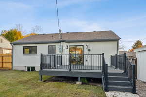 Back of property featuring brick siding, a deck, and roof with shingles
