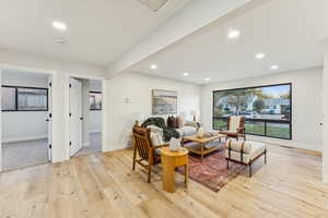 Living area with recessed lighting, light wood-style flooring, and beam ceiling
