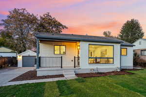 View of front of property featuring covered porch, a lawn, driveway, and brick siding