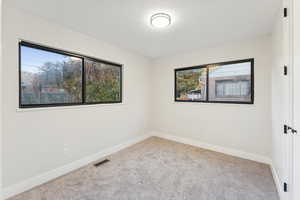 Empty room featuring light carpet and a textured ceiling