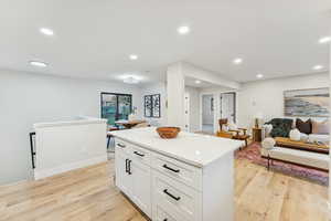 Kitchen featuring recessed lighting, light wood-style floors, a center island, white cabinets, and light stone countertops