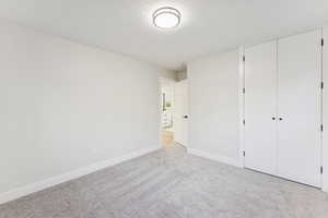 Unfurnished bedroom with a textured ceiling, carpet, and a closet