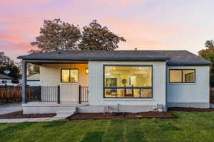 Back of house with brick siding, a yard, and a shingled roof