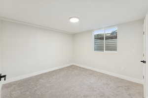 Carpeted spare room featuring baseboards