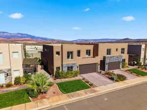 Adobe home with stone siding, stucco siding, concrete driveway, and a mountain view