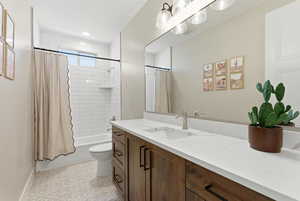 Bathroom with shower / bath combo with shower curtain, vanity, light tile patterned floors, and recessed lighting