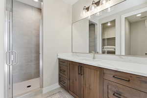 Bathroom featuring light tile patterned flooring, vanity, recessed lighting, a shower stall, and a walk in closet