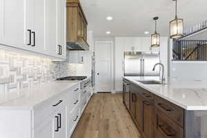 Kitchen with recessed lighting, a kitchen island with sink, light wood-style floors, white cabinetry, and tasteful backsplash
