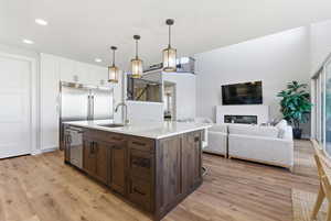 Kitchen featuring dark brown cabinetry, hanging light fixtures, white cabinets, light wood-type flooring, and a kitchen breakfast bar