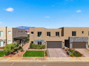 View of front of home featuring stone siding, concrete driveway, a mountain view, and stucco siding