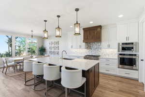 Kitchen featuring tasteful backsplash, white cabinetry, a breakfast bar, decorative light fixtures, and recessed lighting