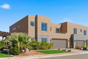 View of front of house with stone siding, stucco siding, concrete driveway, and an attached garage