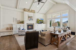 Living room with beamed ceiling, wood-type flooring, a fireplace, high vaulted ceiling, and ceiling fan