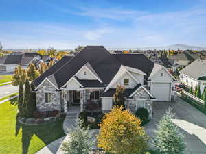 Craftsman-style home featuring stone siding, concrete driveway, an attached garage, and a residential view