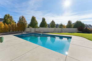 View of swimming pool featuring a diving board, a fenced backyard, and a patio area
