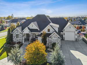 Craftsman-style home featuring stone siding, roof with shingles, concrete driveway, and a standing seam roof