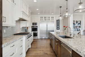Kitchen featuring glass insert cabinets, built in appliances, decorative backsplash, recessed lighting, and dark wood finished floors