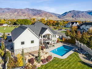 Rear view of house featuring stairs, a patio area, board and batten siding, stone siding, and a fenced backyard