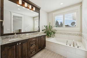 Bathroom with a bath, double vanity, and recessed lighting