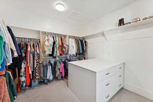 Spacious closet with light carpet and attic access