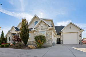 Craftsman inspired home featuring stone siding, concrete driveway, an attached garage, and roof with shingles