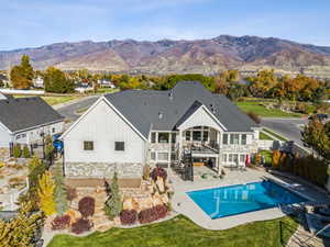 Rear view of property featuring board and batten siding, stairway, a patio area, stone siding, and a mountain view