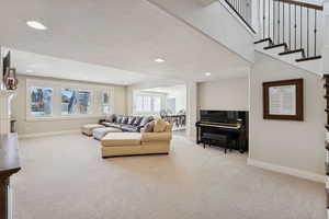 Living area with light colored carpet, recessed lighting, and a textured ceiling