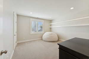 Living area with light carpet and recessed lighting