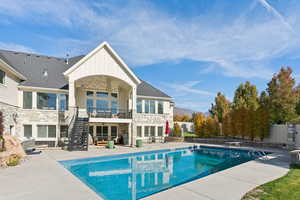 Back of property with stone siding, a patio area, stairway, a mountain view, and board and batten siding