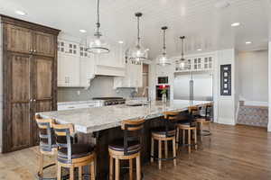 Kitchen featuring glass insert cabinets, backsplash, a kitchen breakfast bar, dark wood-type flooring, and recessed lighting