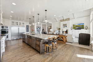 Kitchen featuring glass insert cabinets, pendant lighting, built in appliances, white cabinets, and dark brown cabinets