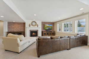 Living area featuring a brick fireplace, light colored carpet, recessed lighting, and brick wall