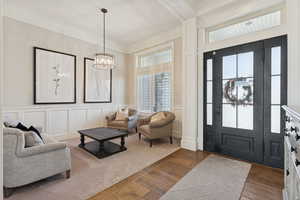 Foyer entrance featuring a decorative wall, ornamental molding, and wood finished floors
