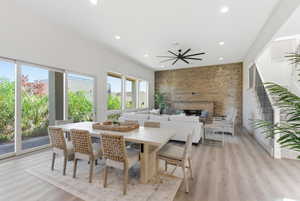 Dining area with an accent wall, a large fireplace, light wood-type flooring, recessed lighting, and wood walls