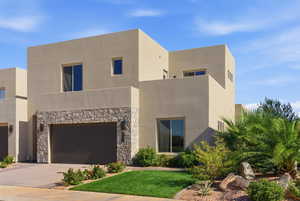 View of front of property featuring stone siding, stucco siding, driveway, an attached garage, and a front lawn