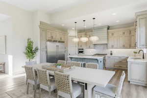 Kitchen featuring a center island, a breakfast bar area, high quality appliances, hanging light fixtures, and light stone counters