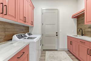 Laundry area featuring light wood-style floors, cabinet space, and washing machine and clothes dryer