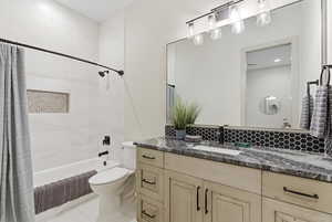 Bathroom featuring vanity, shower / tub combo, and backsplash