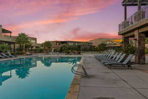 Pool at dusk with a patio area, a community pool, a mountain view, and a pergola