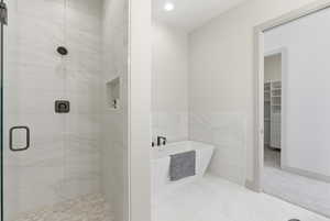Full bathroom with a soaking tub, a stall shower, a spacious closet, and recessed lighting