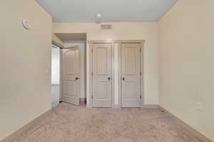 Unfurnished bedroom featuring light carpet, a closet, and a textured ceiling