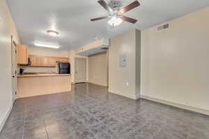 Unfurnished living room featuring dark tile patterned flooring, a ceiling fan, and electric panel