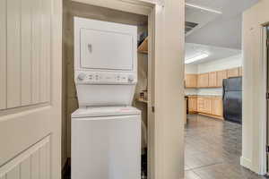Washroom featuring light tile patterned floors and stacked washer / dryer